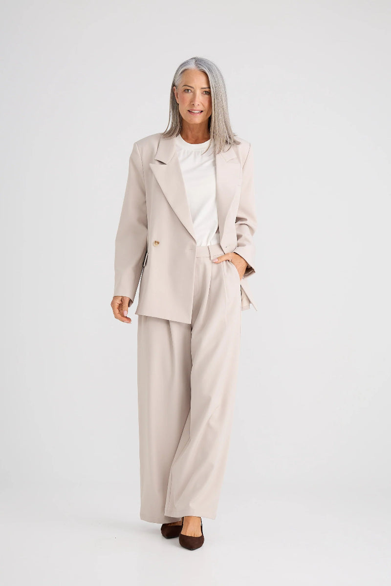 Woman wearing a beige suit with a white shirt on a white background