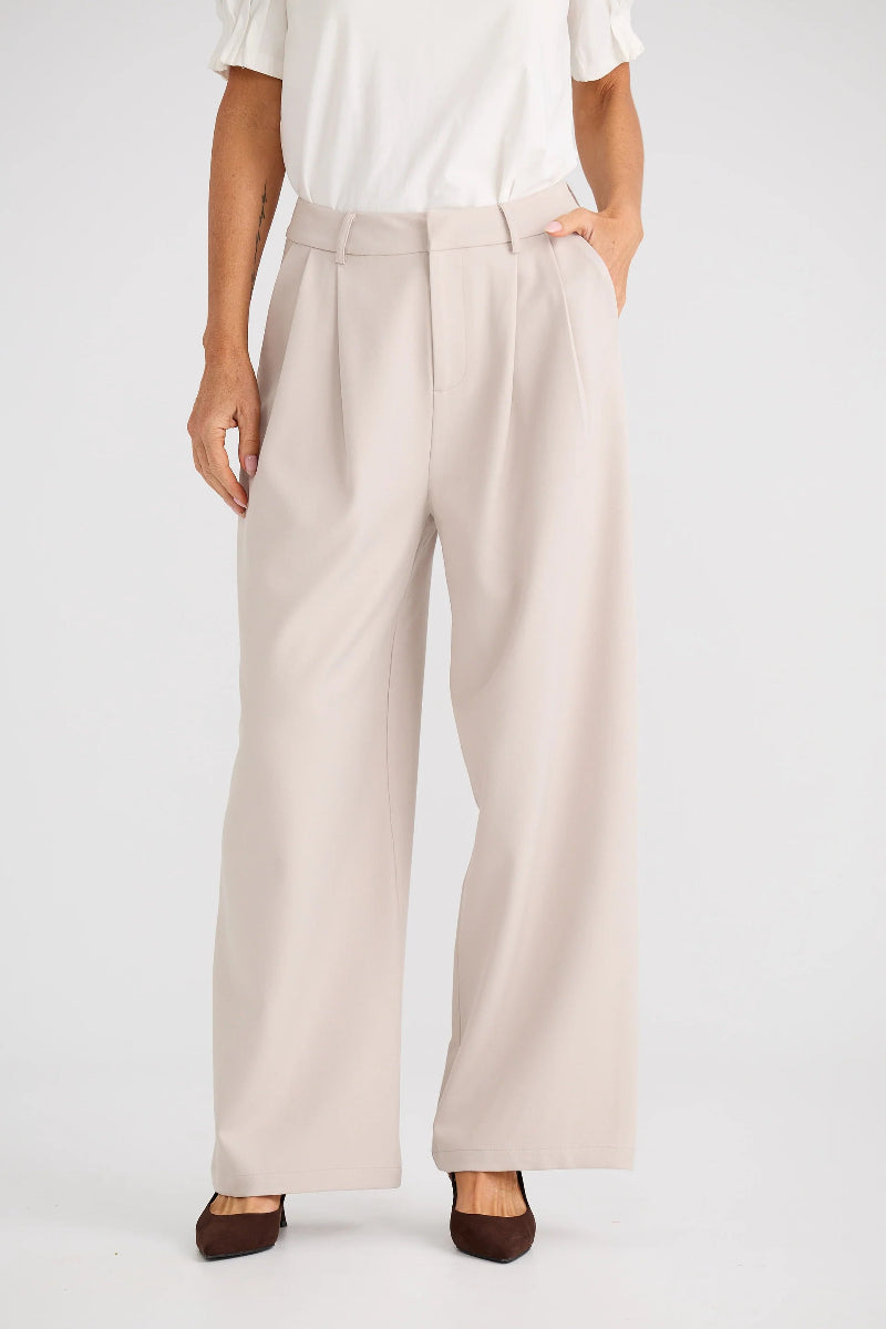Person wearing beige wide-leg pants on a white background