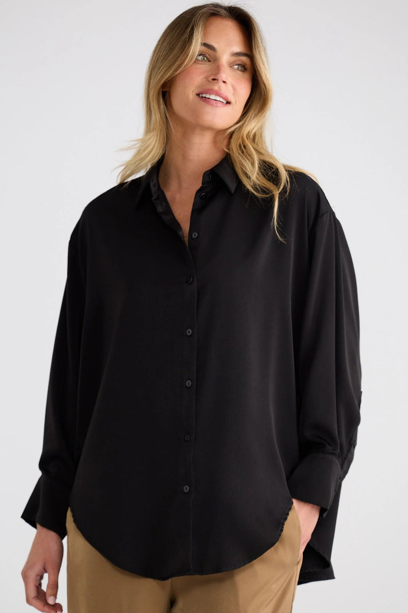 Woman wearing a black shirt and beige pants on a white background