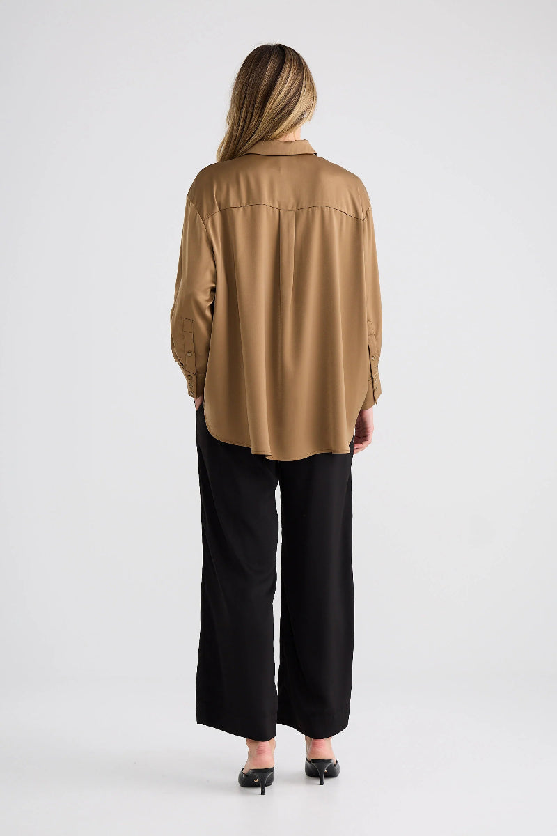 Person wearing a tan blouse and black pants on a white background