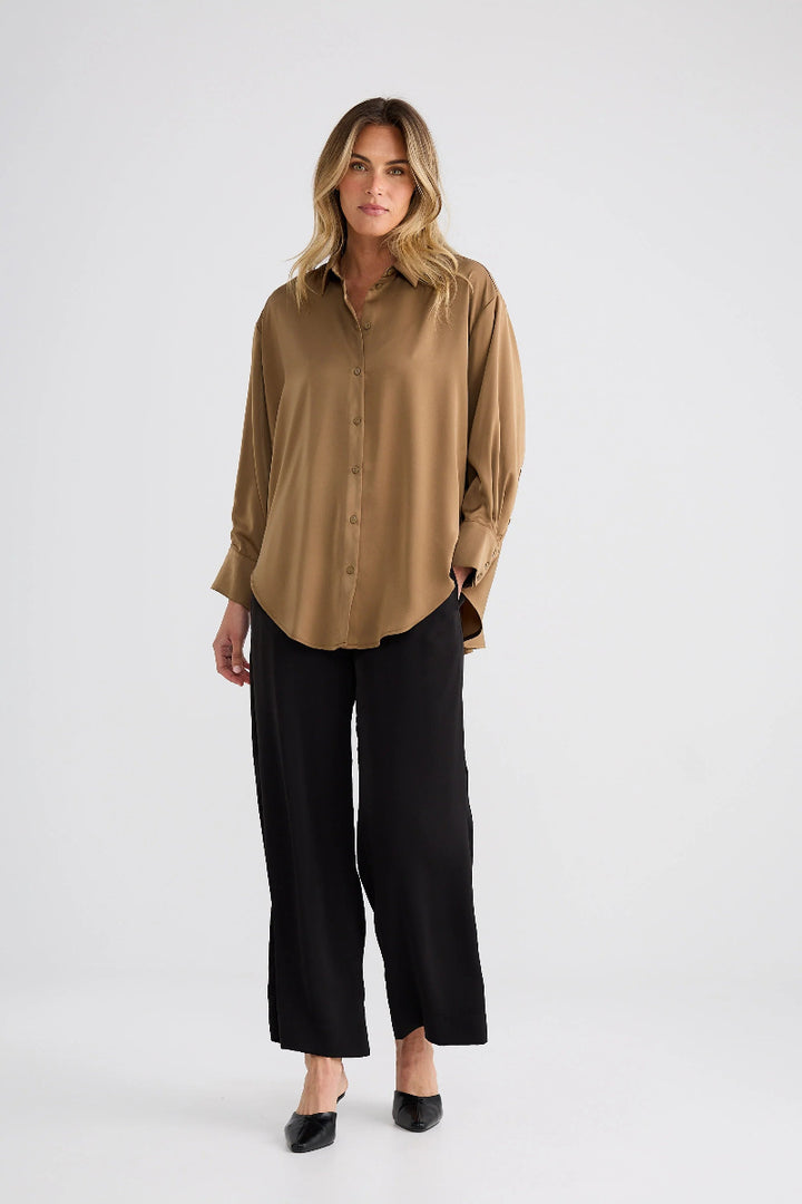 Woman wearing a beige shirt and black pants on a white background