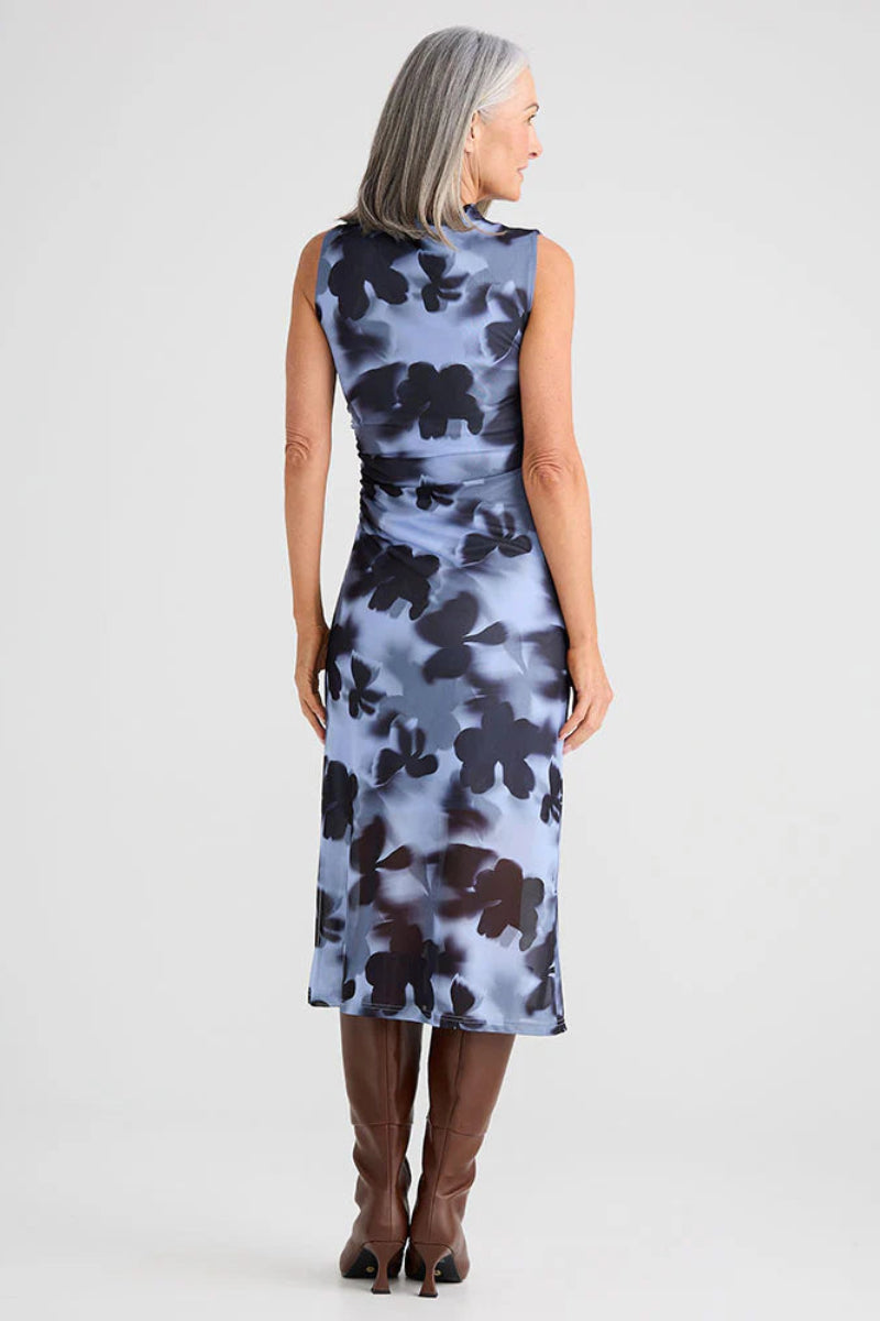 Woman wearing a sleeveless dress with floral pattern on a plain background