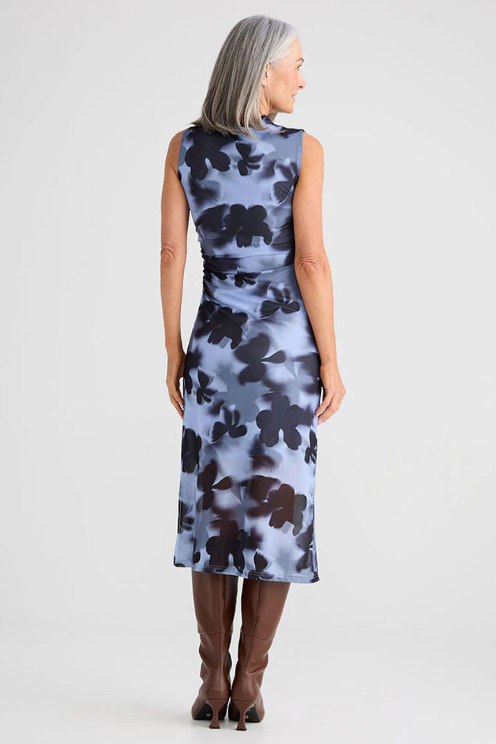 Woman wearing a sleeveless dress with floral pattern on a plain background