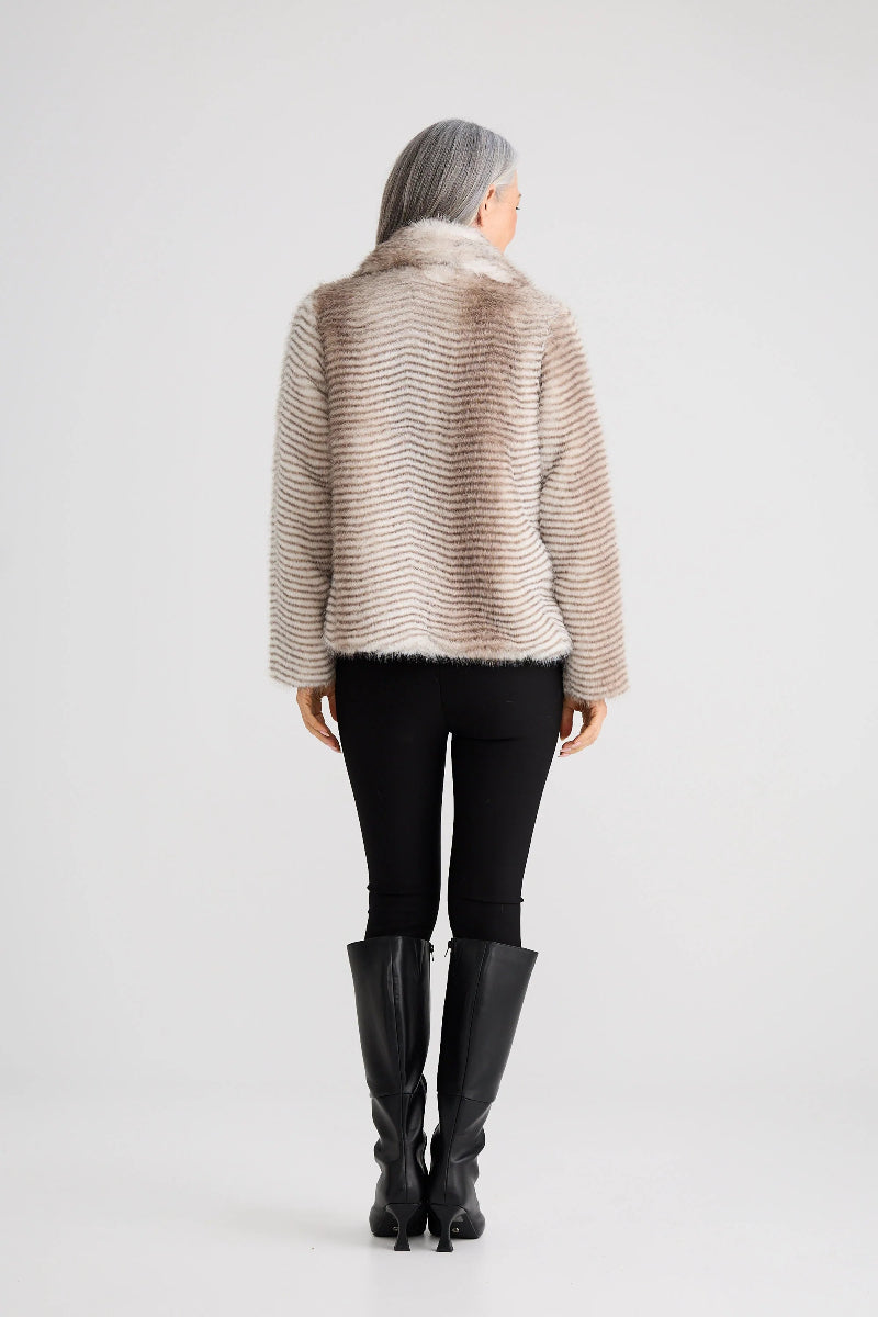 Person wearing a beige knitted sweater, black pants, and black boots on a white background
