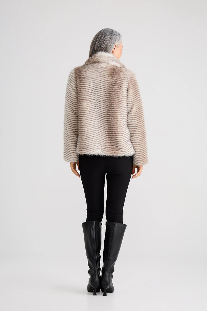 Person wearing a beige knitted sweater, black pants, and black boots on a white background