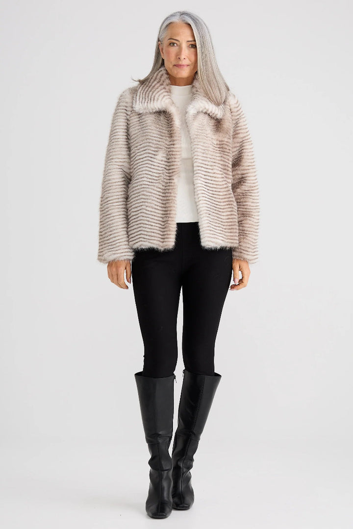 Woman wearing a fur-trimmed coat, black leggings, and black boots on a white background