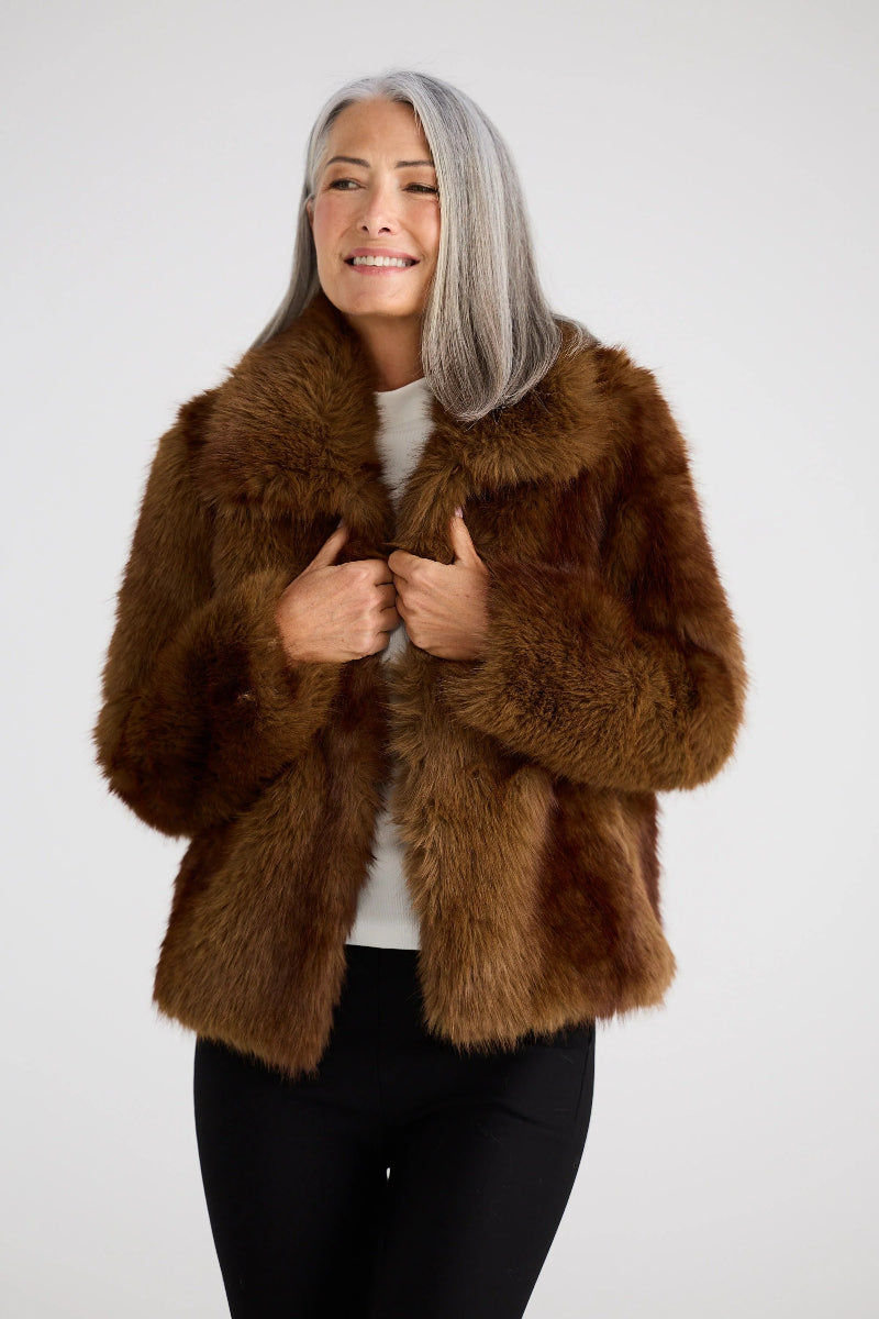 Woman wearing a brown fur coat against a white background