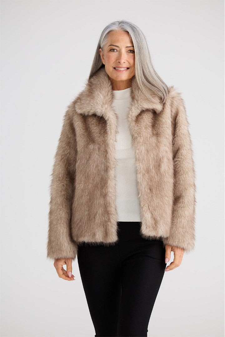 Woman wearing a beige faux fur jacket on a white background