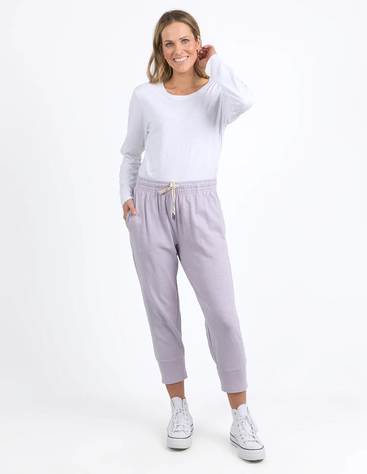 Woman wearing a white long-sleeve top and light gray sweatpants on a white background