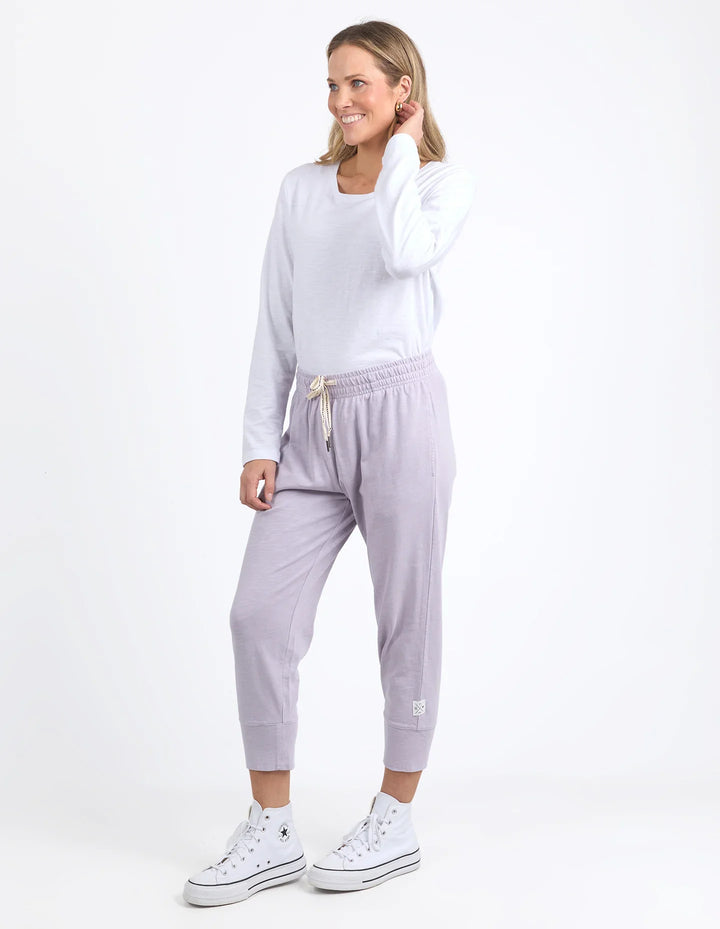 Woman wearing a white sweatshirt and light purple jogger pants on a white background
