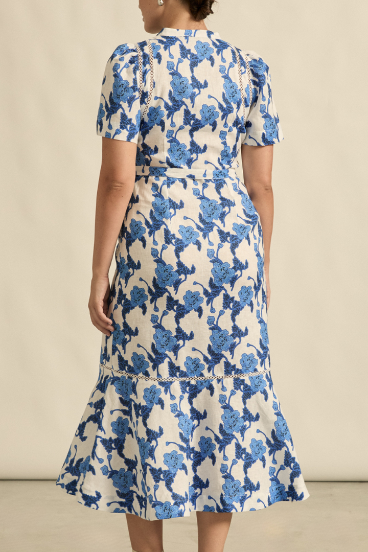 This back view of the Cable Dress in Azure Bouquet highlights its flowing A-line shape, self-tie belt, and subtle back detailing, creating an effortlessly elegant look.
