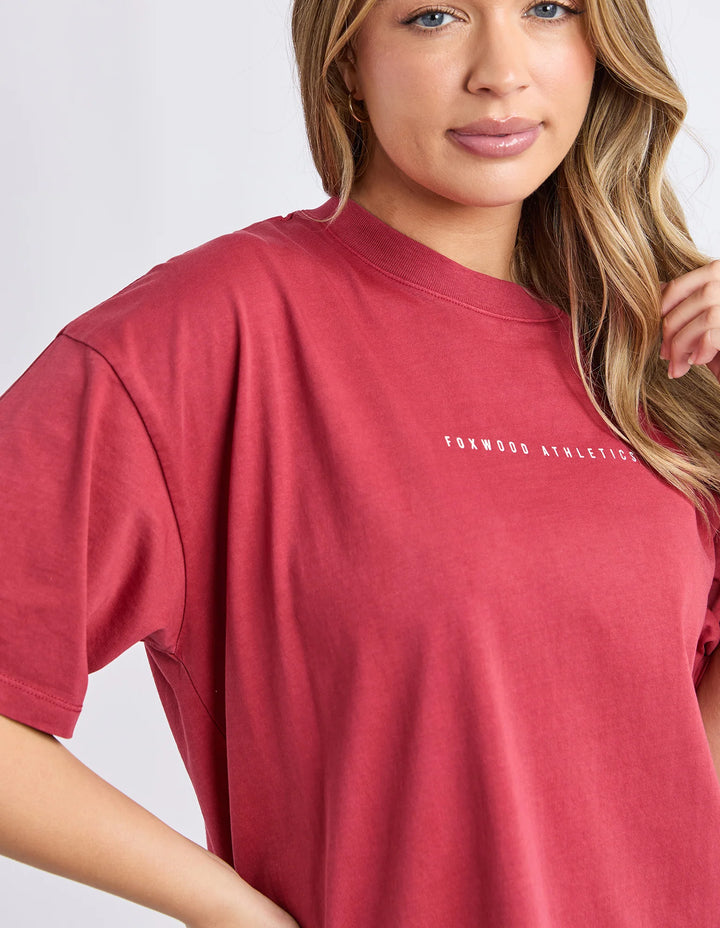 Women wearing a relaxed fit rust captain tee short sleeve Foxwood athletics print on top against a neutral background.