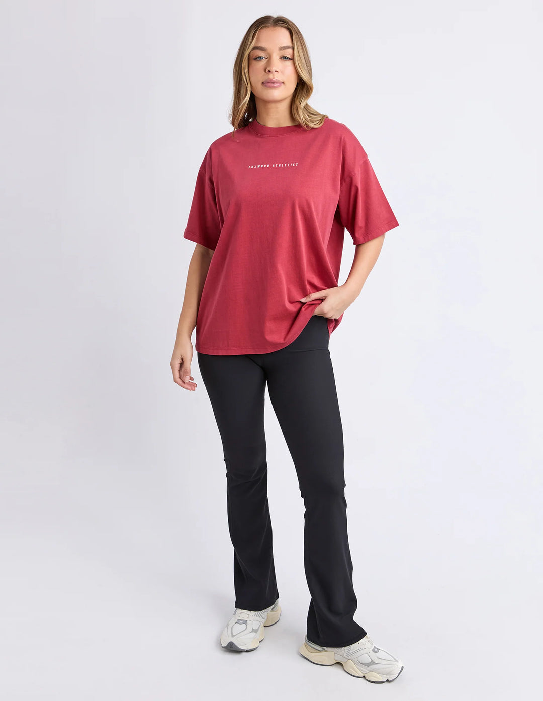 Women wearing a relaxed fit rust captain tee short sleeve Foxwood athletics print on top with black plants against a neutral background.