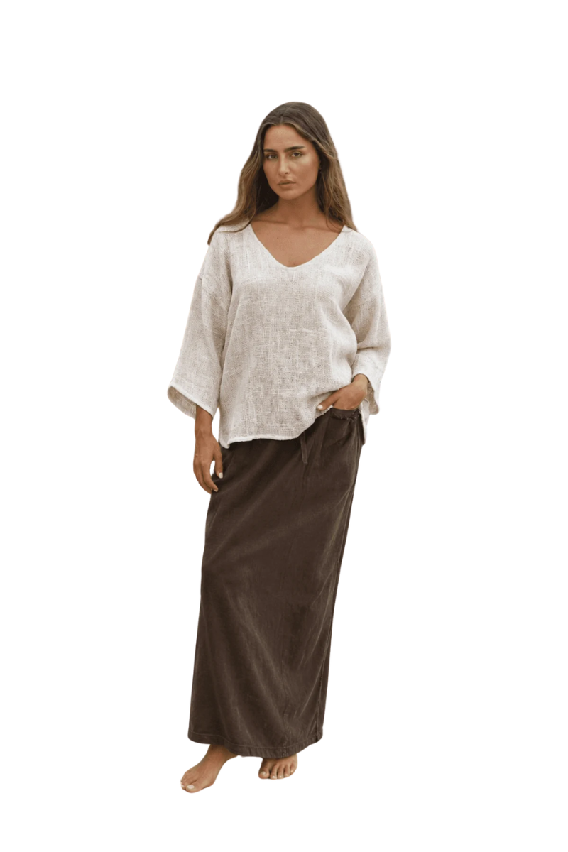 Woman wearing a beige top and brown skirt on a white background