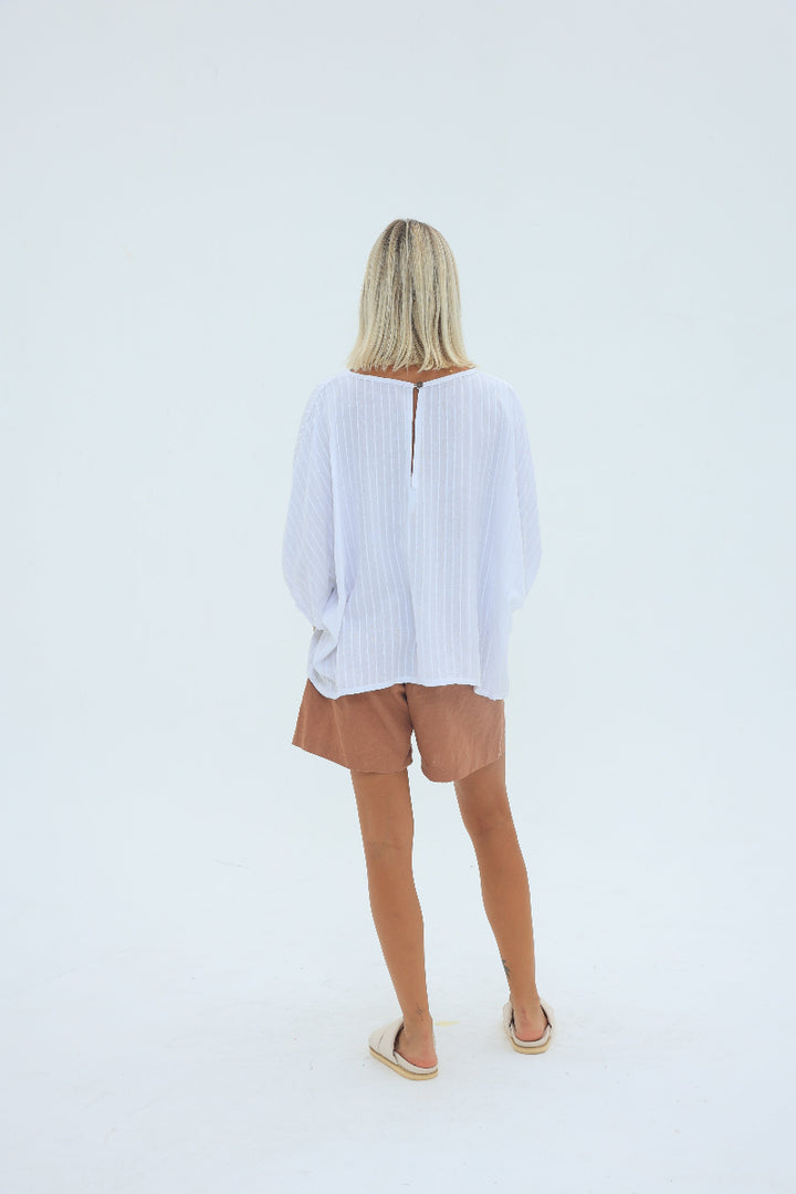 Person wearing a white shirt and brown shorts on a light gray background
