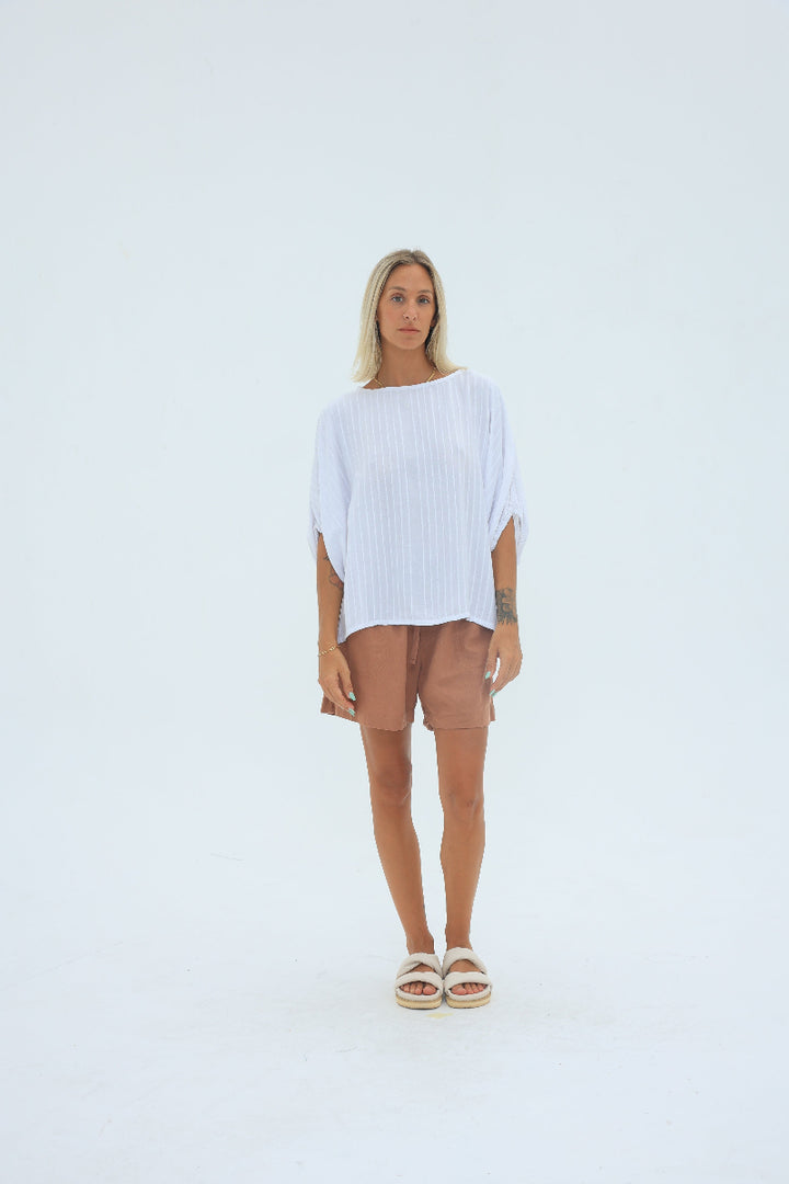 Person wearing a white dress standing on a light gray background