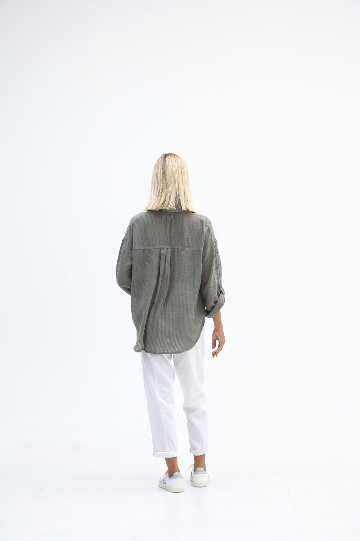 Person wearing a gray coat and white pants on a white background