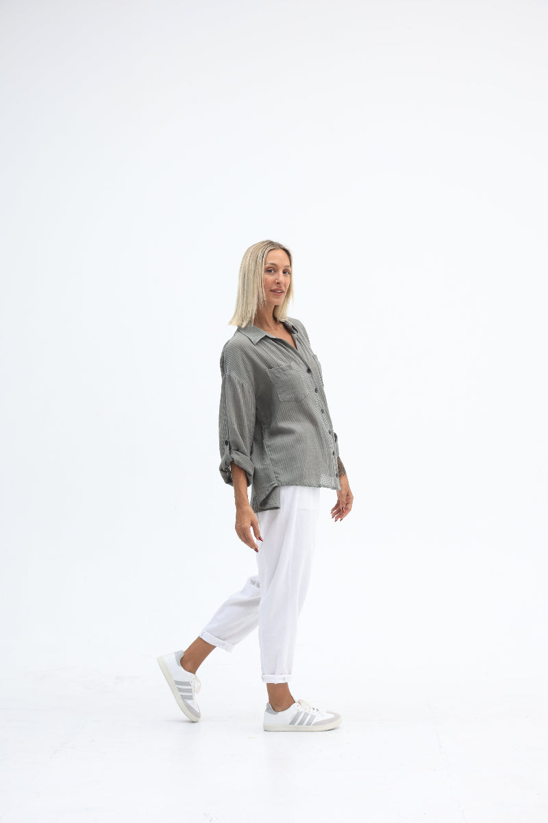 Person wearing a gray jacket and white pants on a white background
