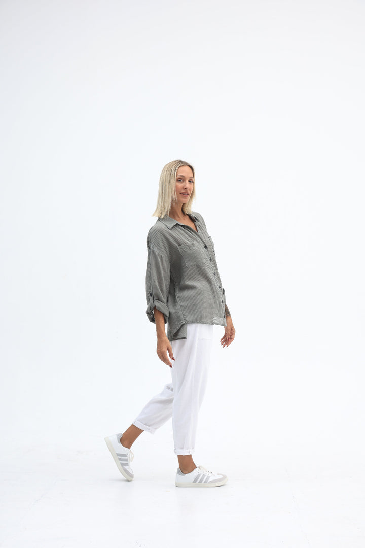 Person wearing a gray jacket and white pants on a white background