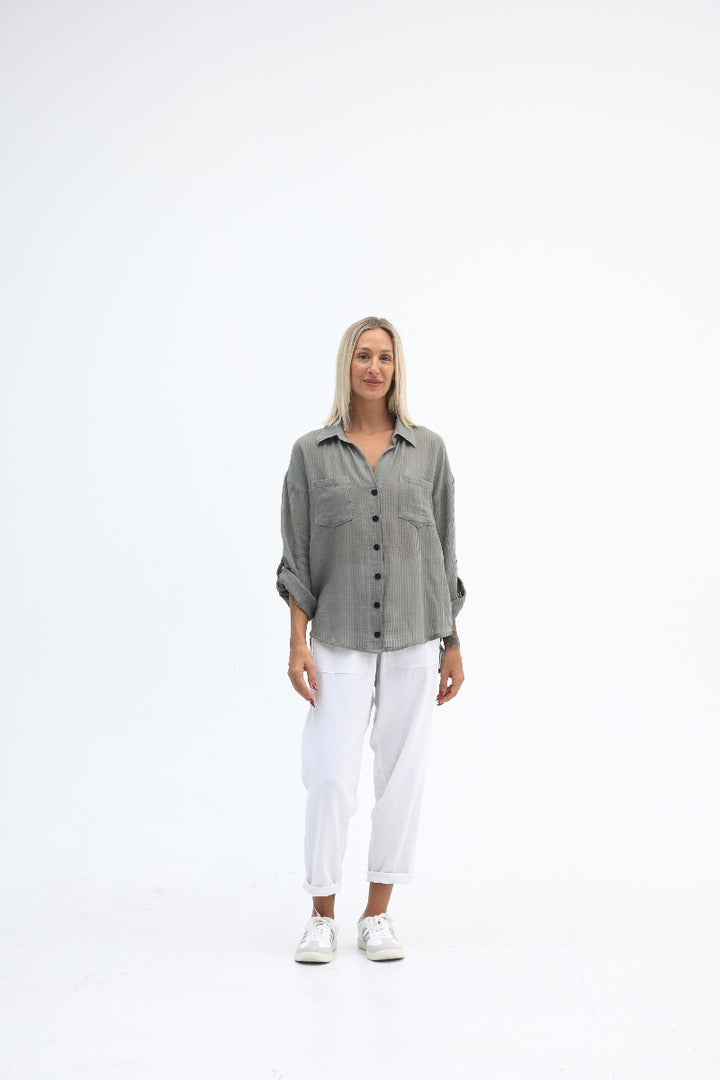 Person wearing a gray jacket and white pants on a white background