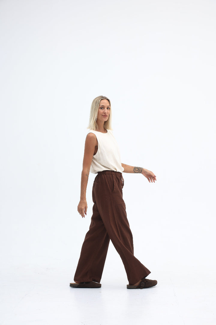 Person lying on a white background with a white shirt and brown pants.