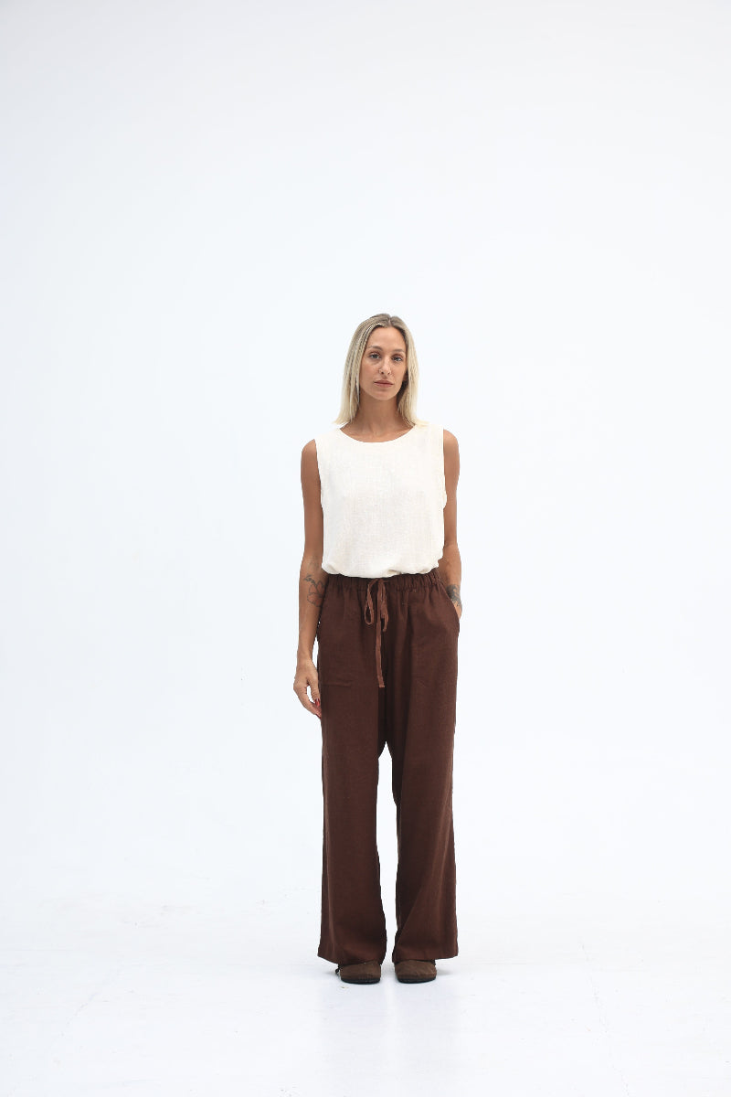 Person wearing a white top and brown pants on a white background