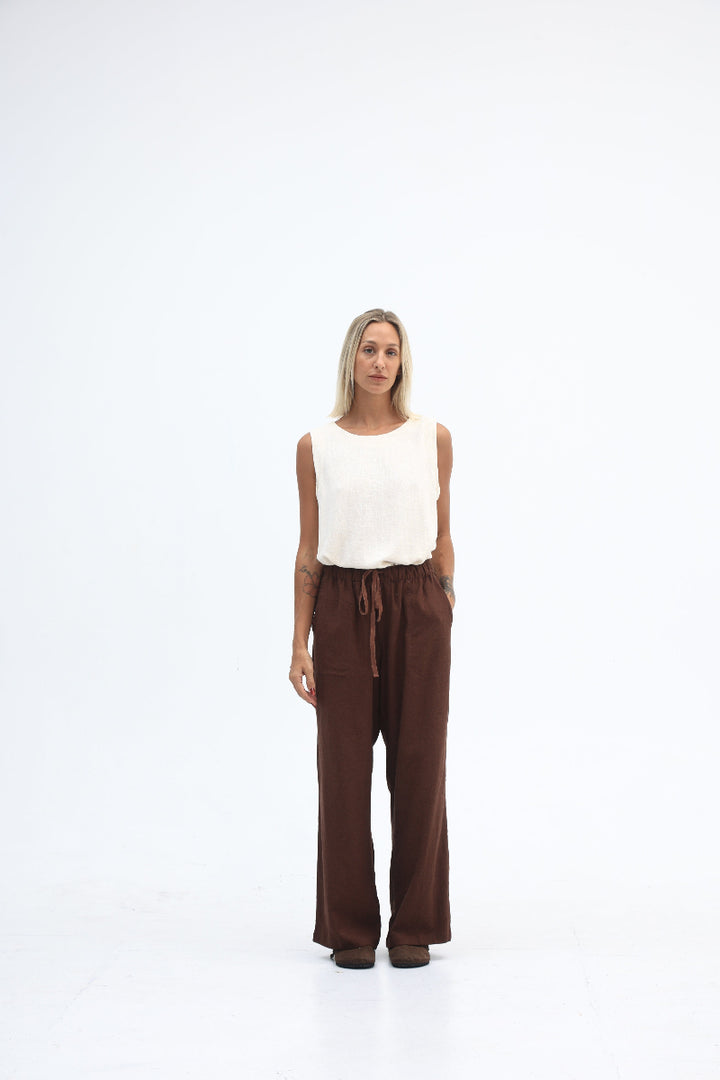 Person wearing a white top and brown pants on a white background