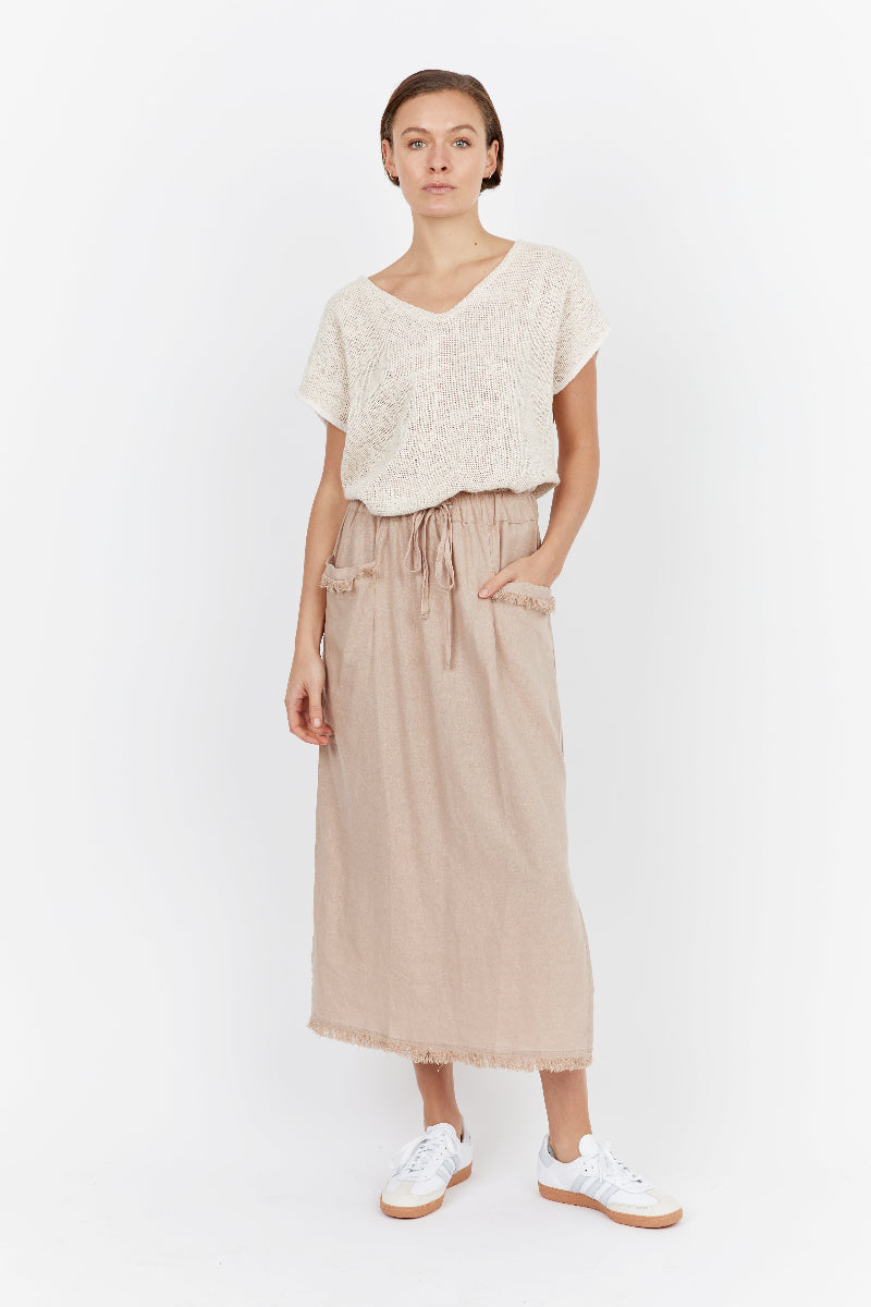Woman wearing a white top and beige skirt on a white background