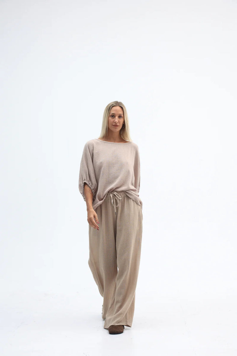 Woman wearing a beige jumpsuit on a white background