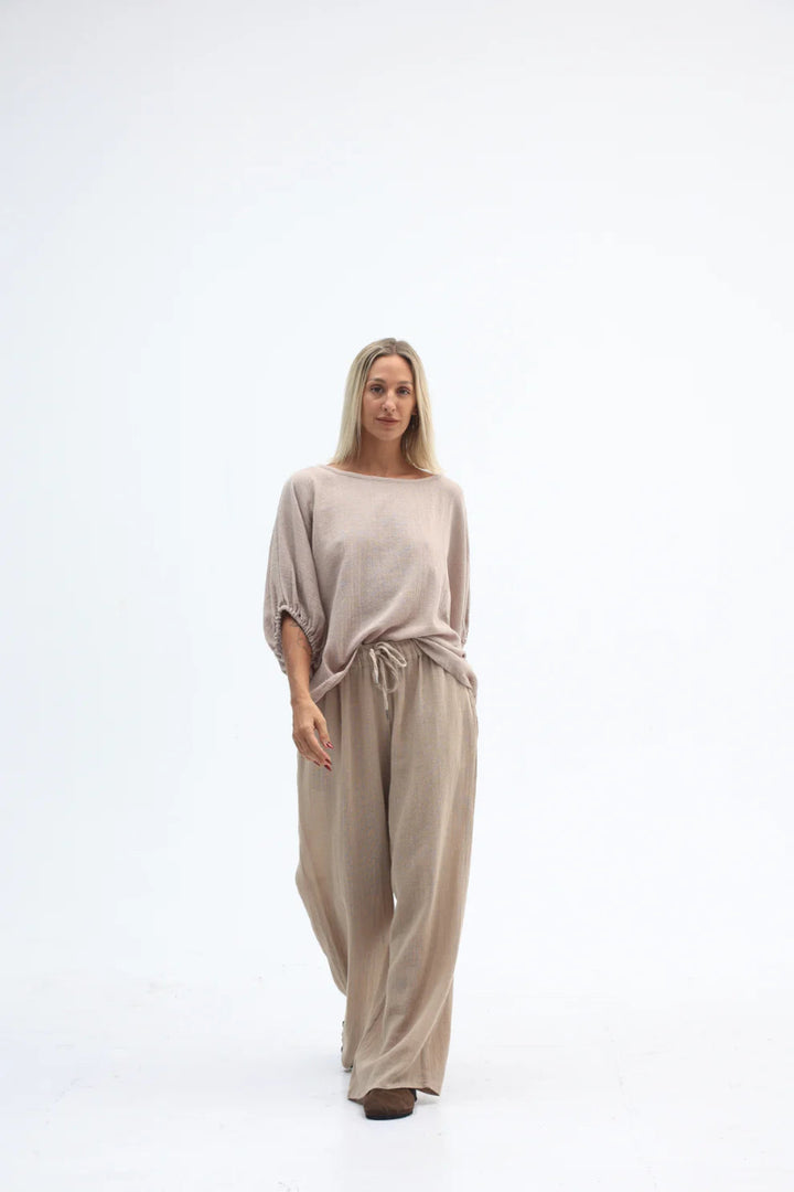 Woman wearing a beige jumpsuit on a white background