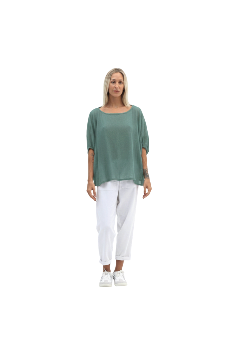 Woman wearing a green top and white pants on a white background