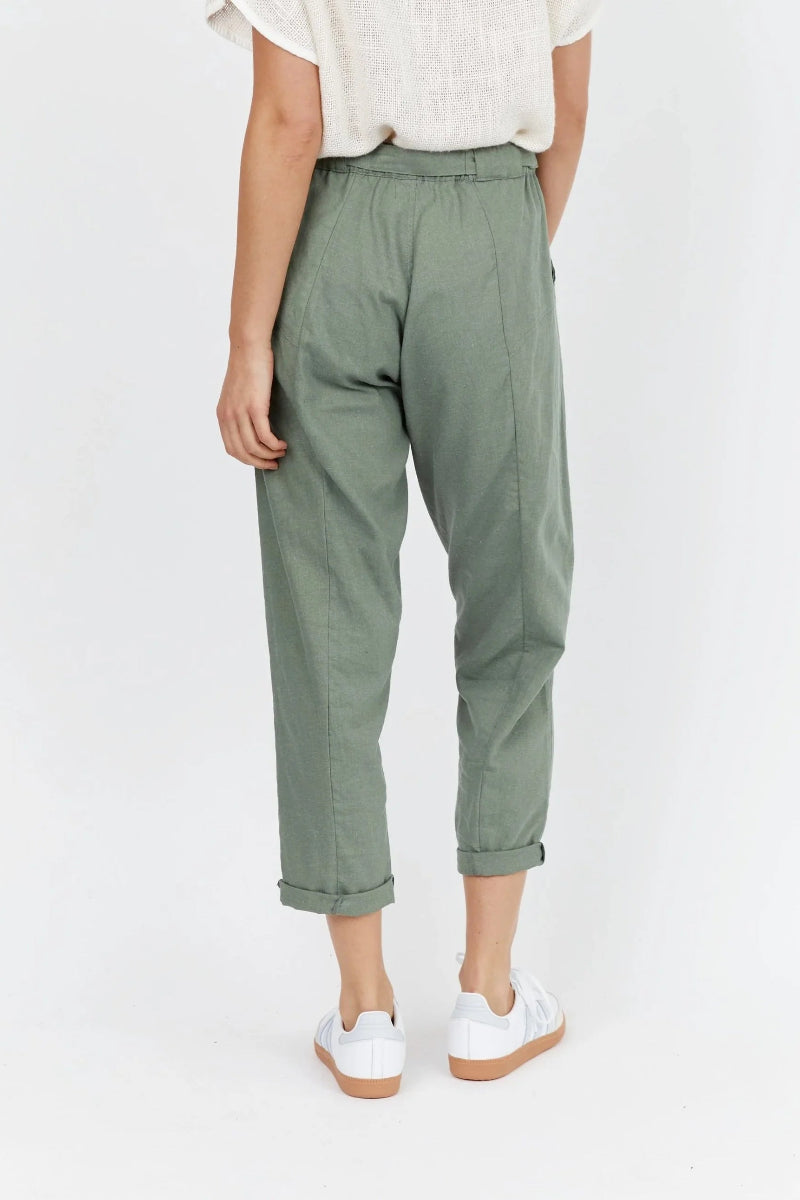 Person wearing green pants and white sneakers on a white background