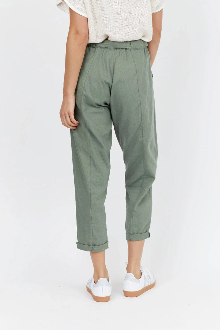 Person wearing green pants and white sneakers on a white background