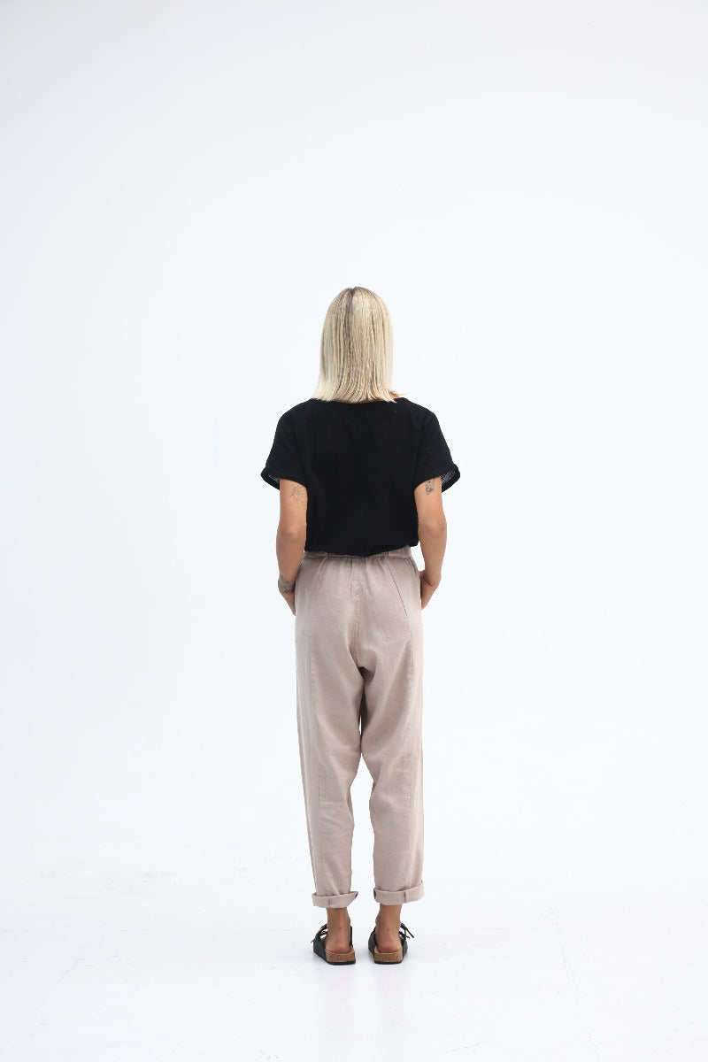 Person wearing a black t-shirt and beige pants on a white background