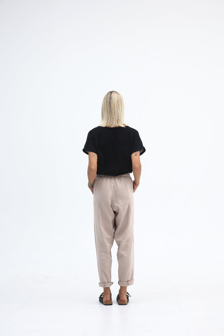 Person wearing a black t-shirt and beige pants on a white background