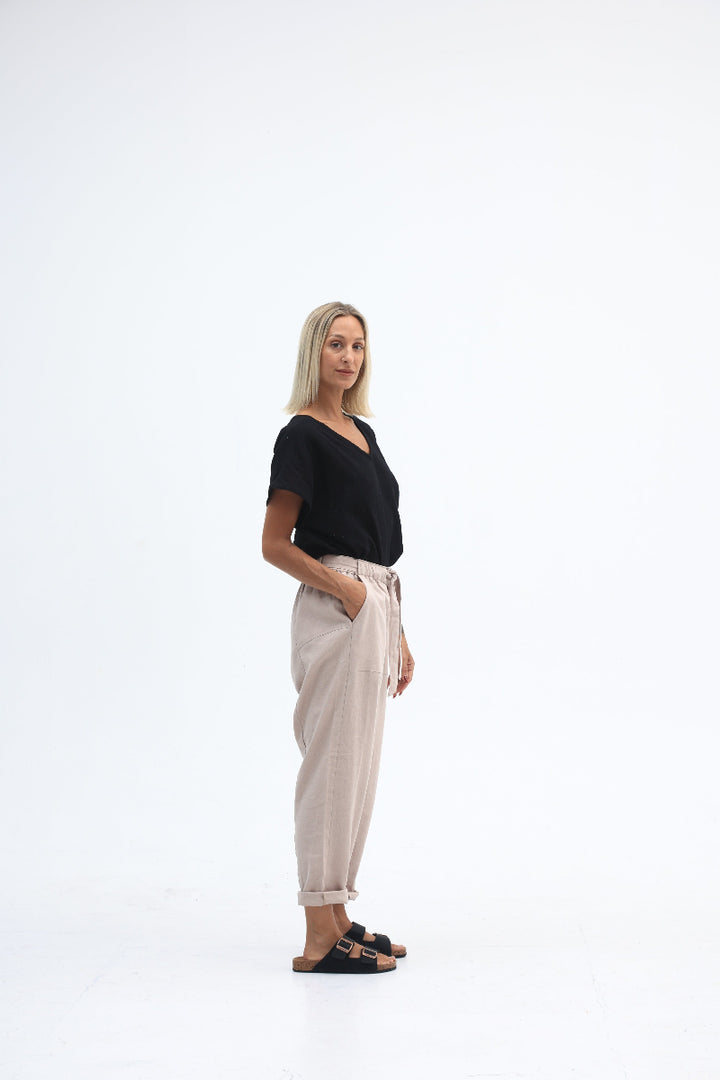 Woman wearing a black top and beige pants on a white background