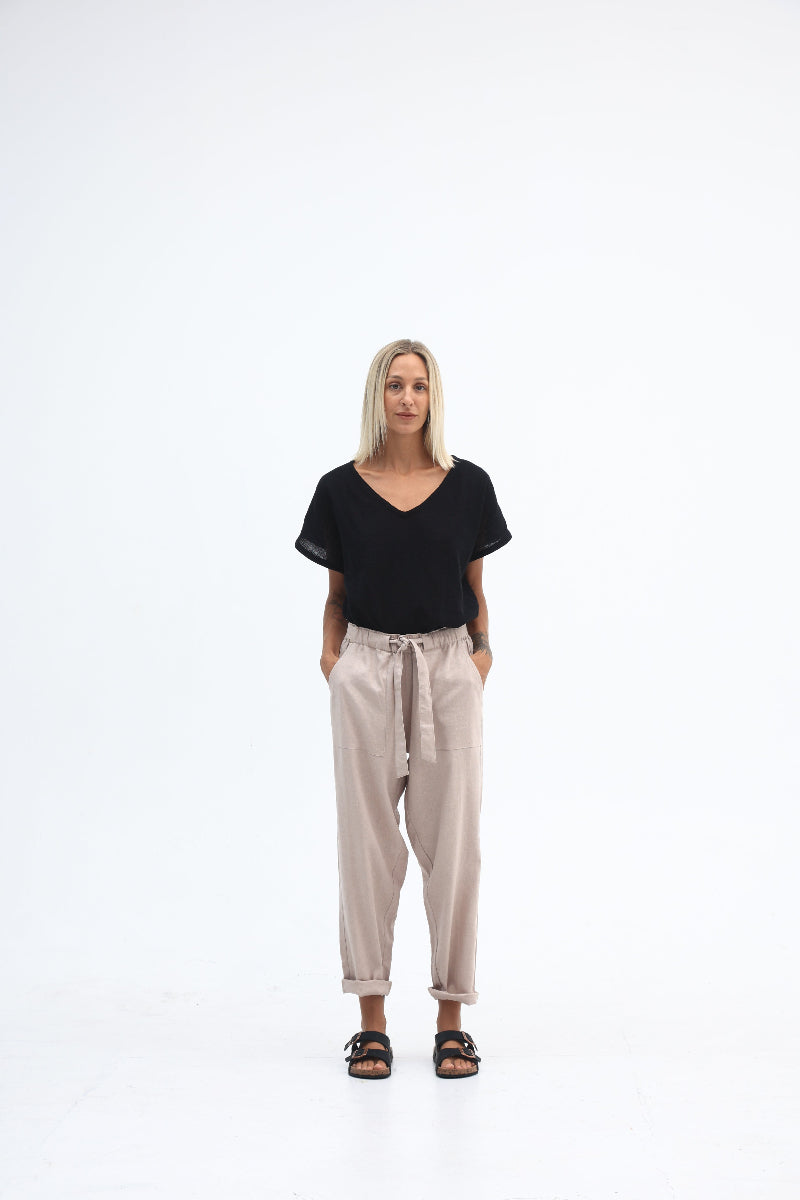 Woman wearing a black top and beige pants on a white background