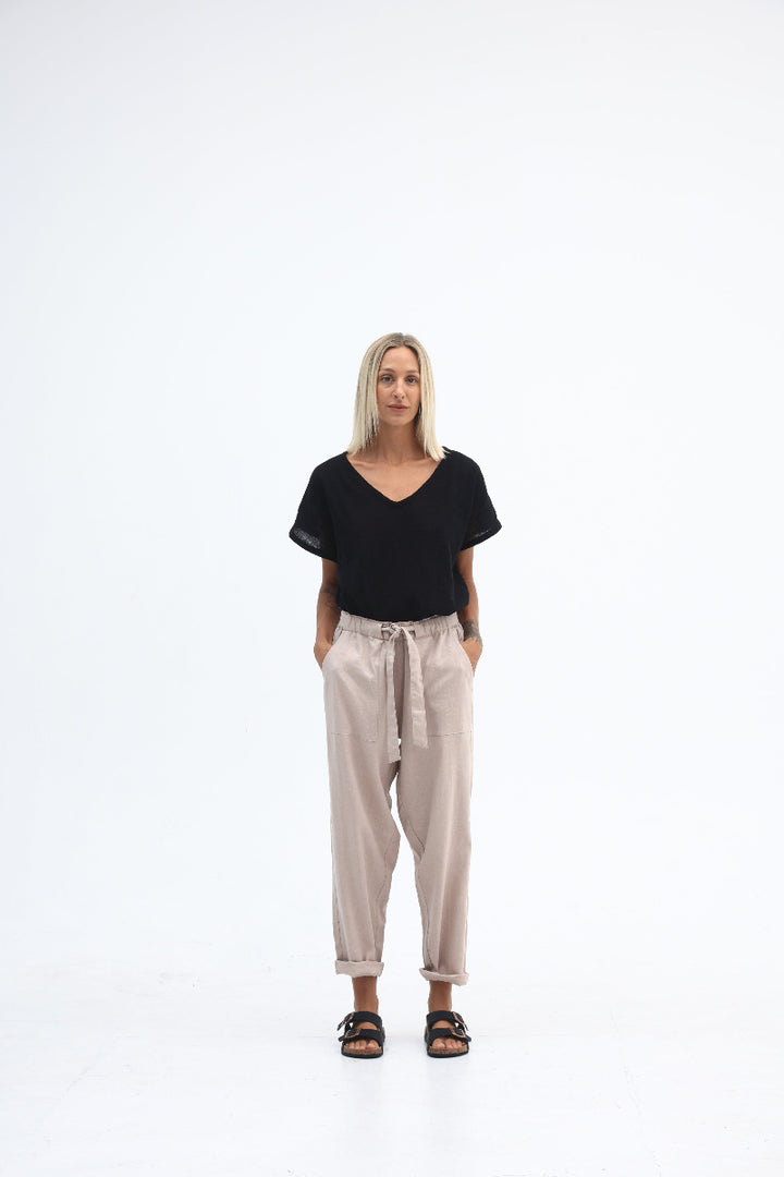 Woman wearing a black top and beige pants on a white background