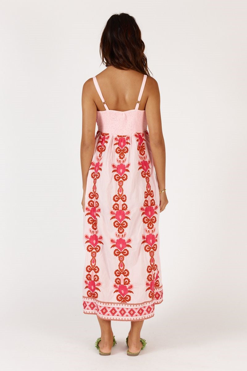 Woman wearing a pink dress with red patterns on a white background
