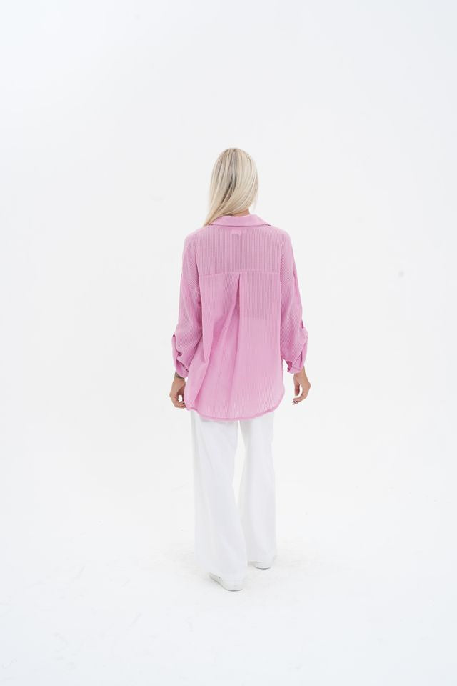 Person wearing a pink shirt and white pants on a white background