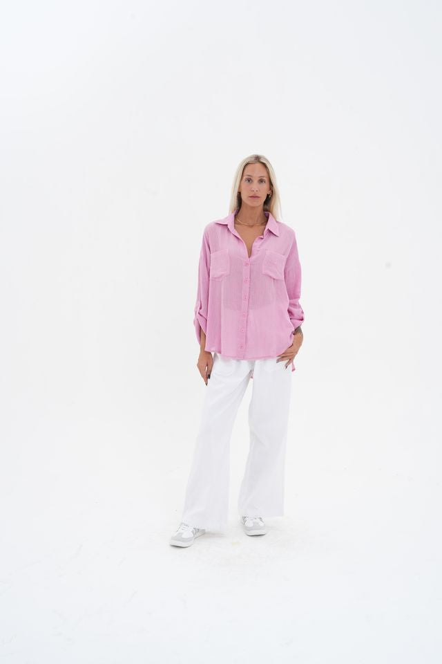Woman wearing a pink shirt and white pants on a white background