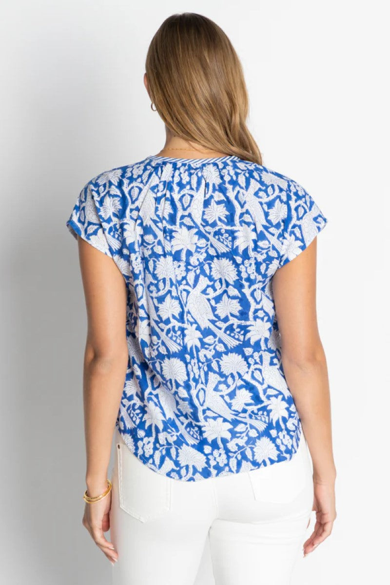 Woman wearing a blue floral patterned top against a white background