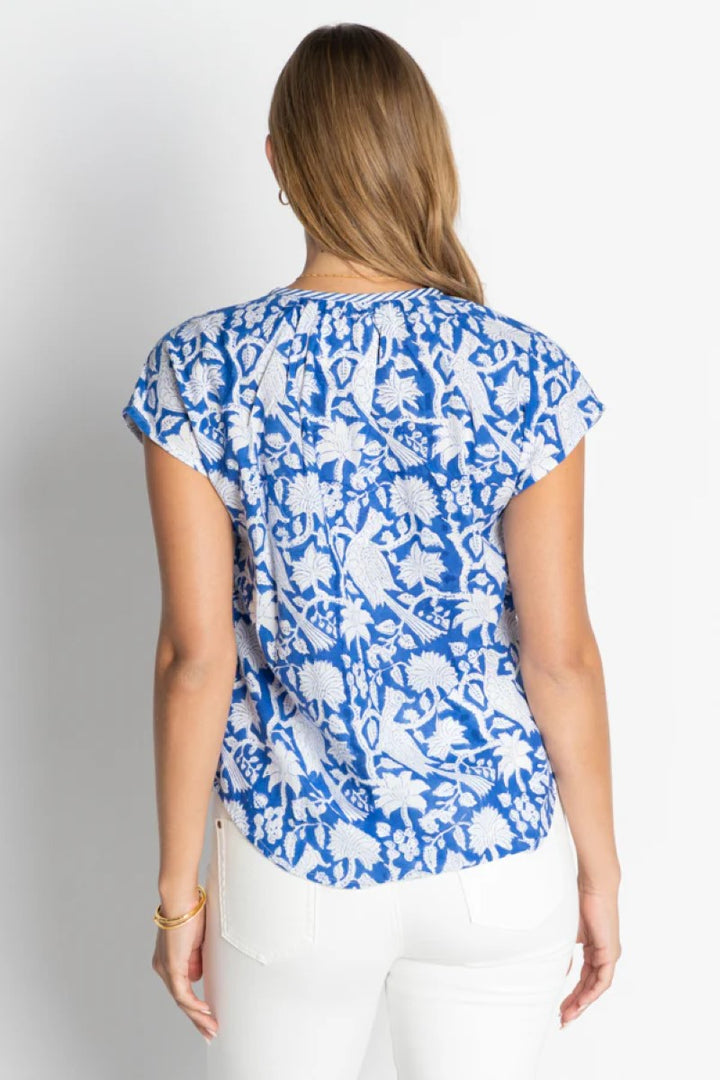 Woman wearing a blue floral patterned top against a white background