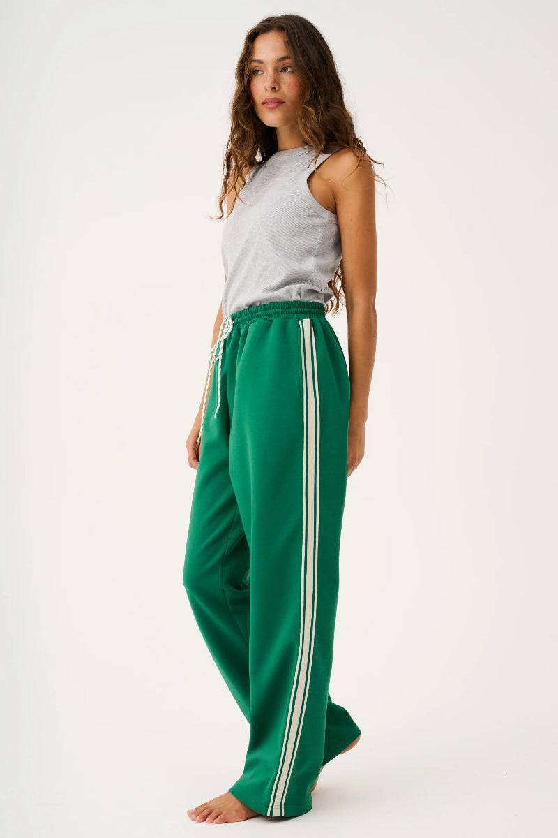 Woman wearing green pants with a white stripe on a white background