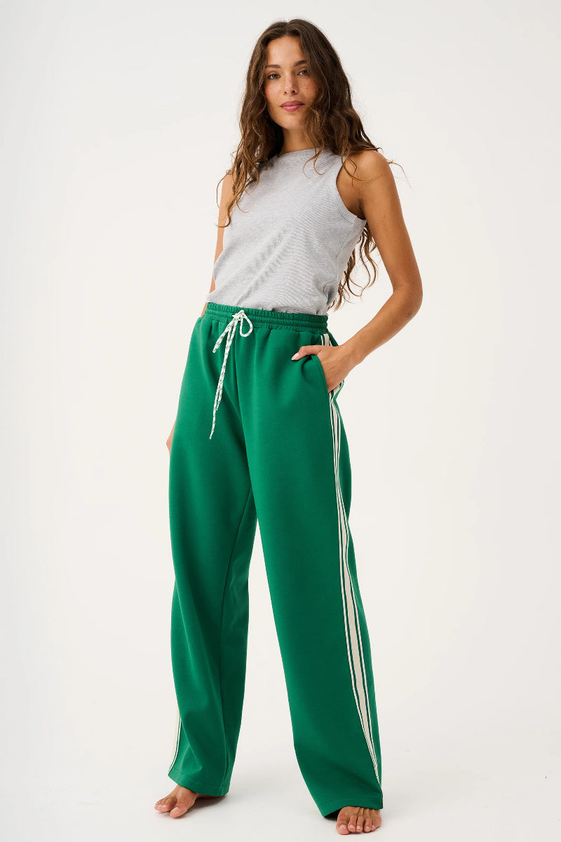 Woman wearing green pants with a white stripe on a white background