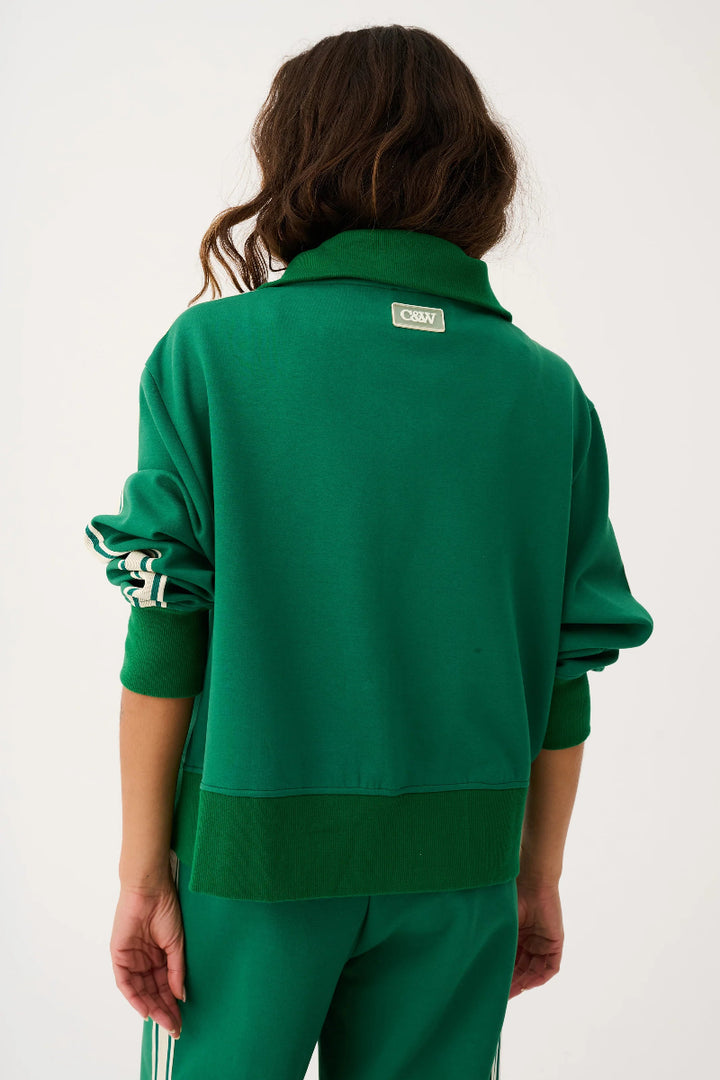 Person wearing a green tracksuit with a visible brand logo on a white background