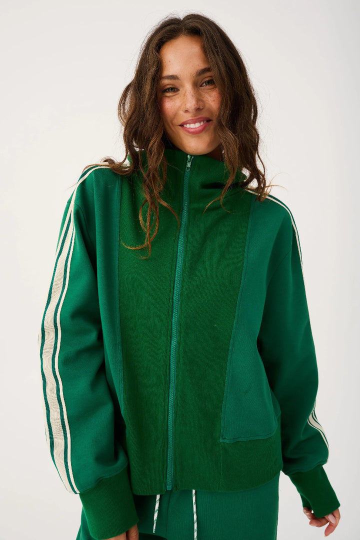 Woman wearing a green tracksuit with white stripes on a white background