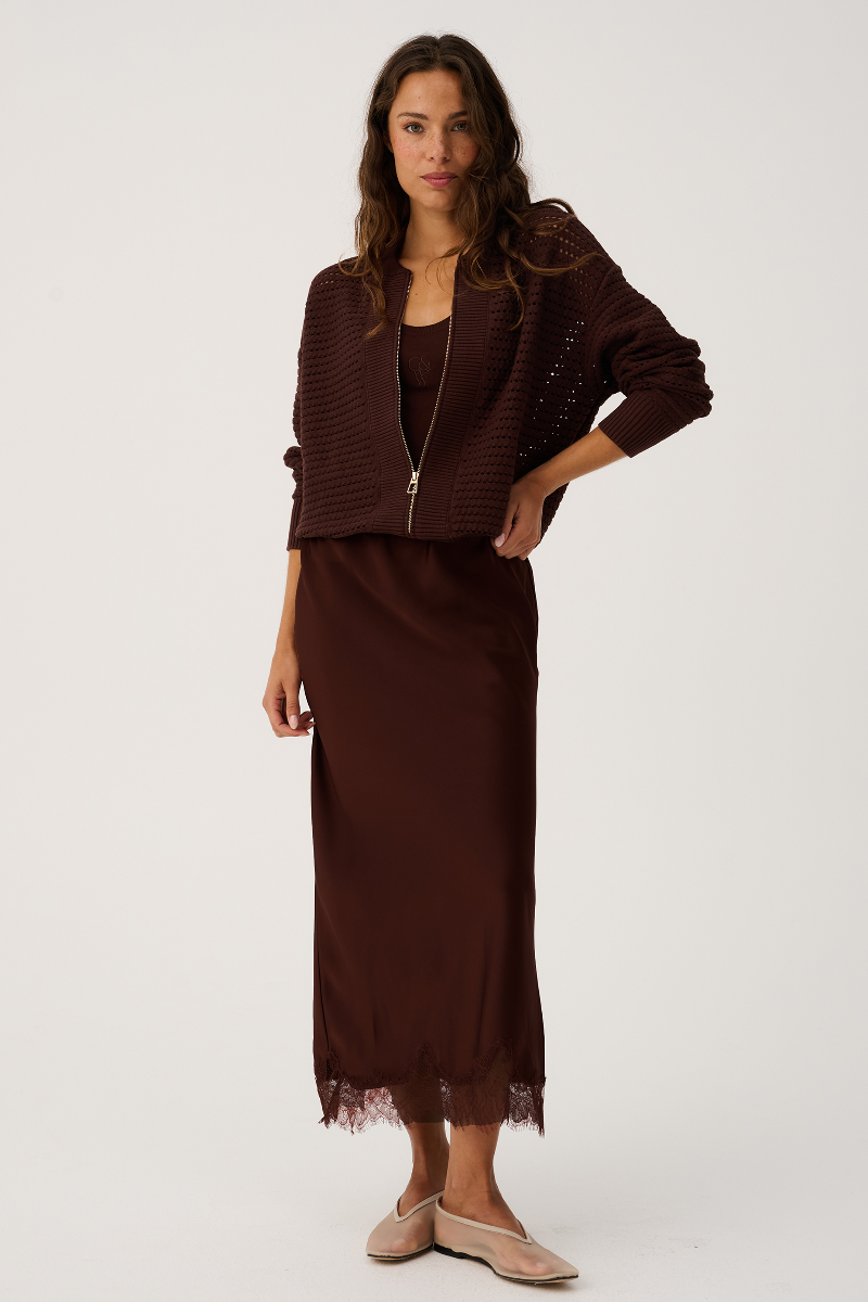 Woman wearing a brown outfit with a jacket and skirt on a white background