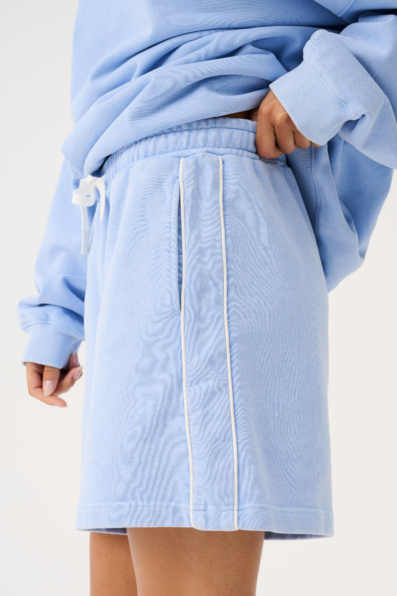 Light blue sweatshirt and skirt worn by a person on a white background