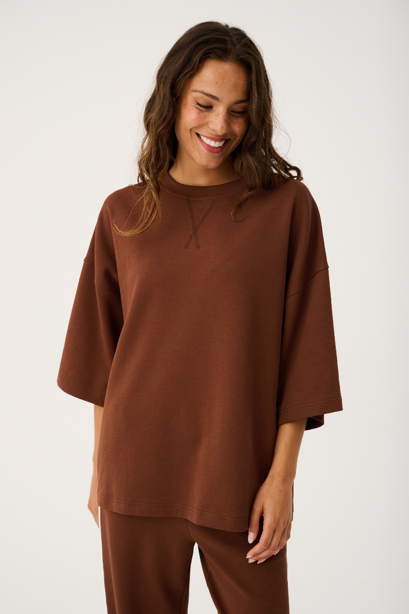 Woman wearing a brown outfit against a white background